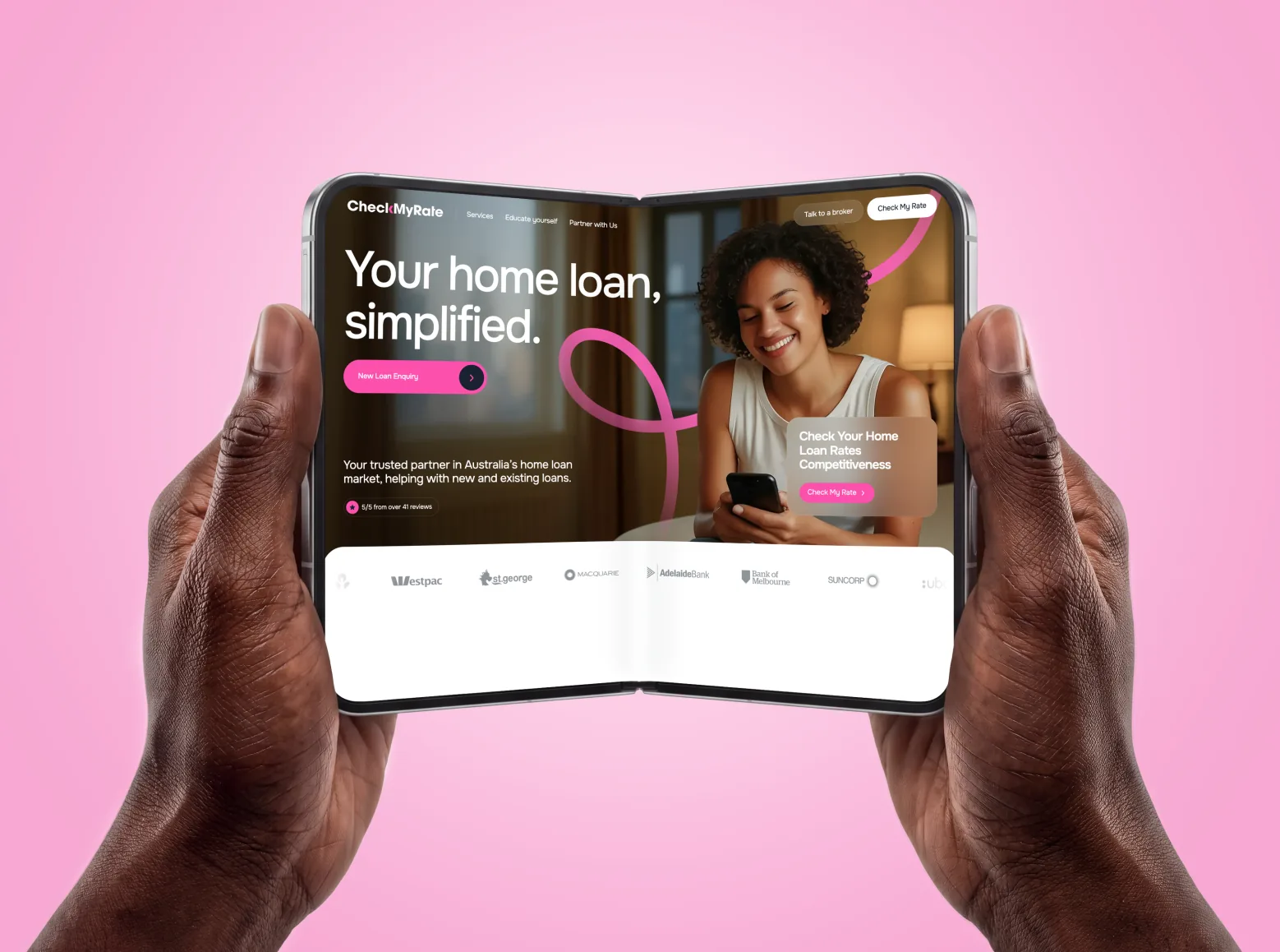 CheckMyRate homepage on a folding phone held in two hands: “Your home loan, simplified.” and the New Loan Enquiry button